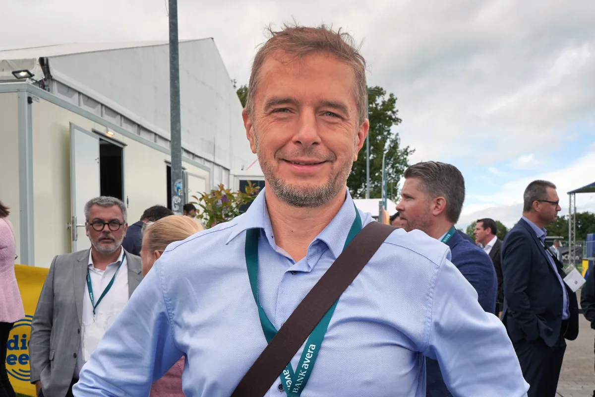 Porträt eines Mannes mit hellblauem Hemd.Man sieht einen Badge und den Gurt einer Tasche über seinem Oberkörper.